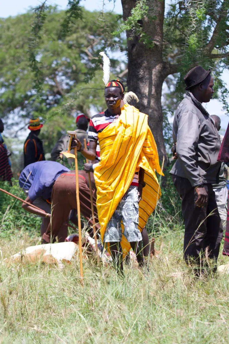 A Karamojong elder in a yellow robe with ceremonial staff