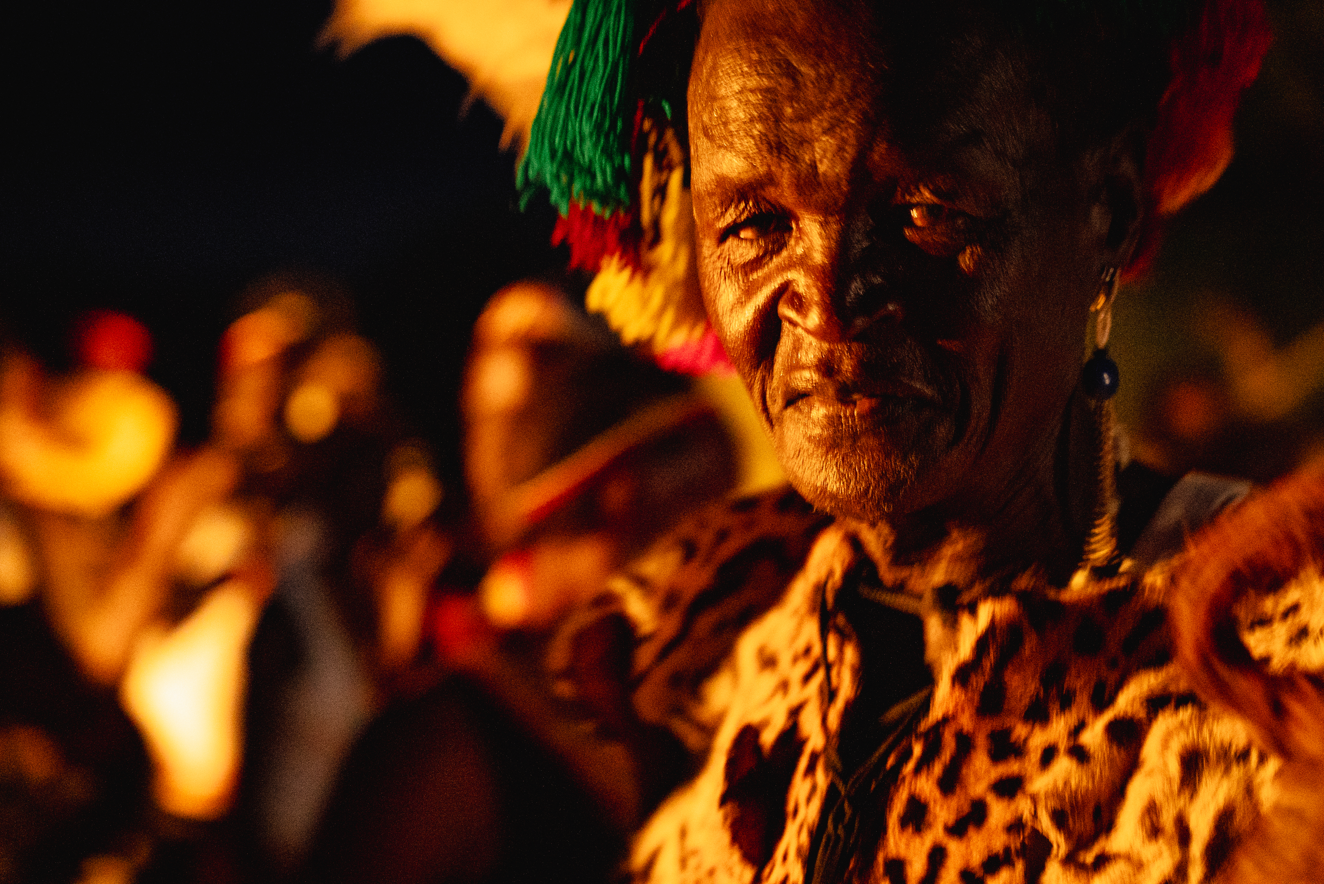 A Karamojong elder in leopard-skin cloak lit by firelight