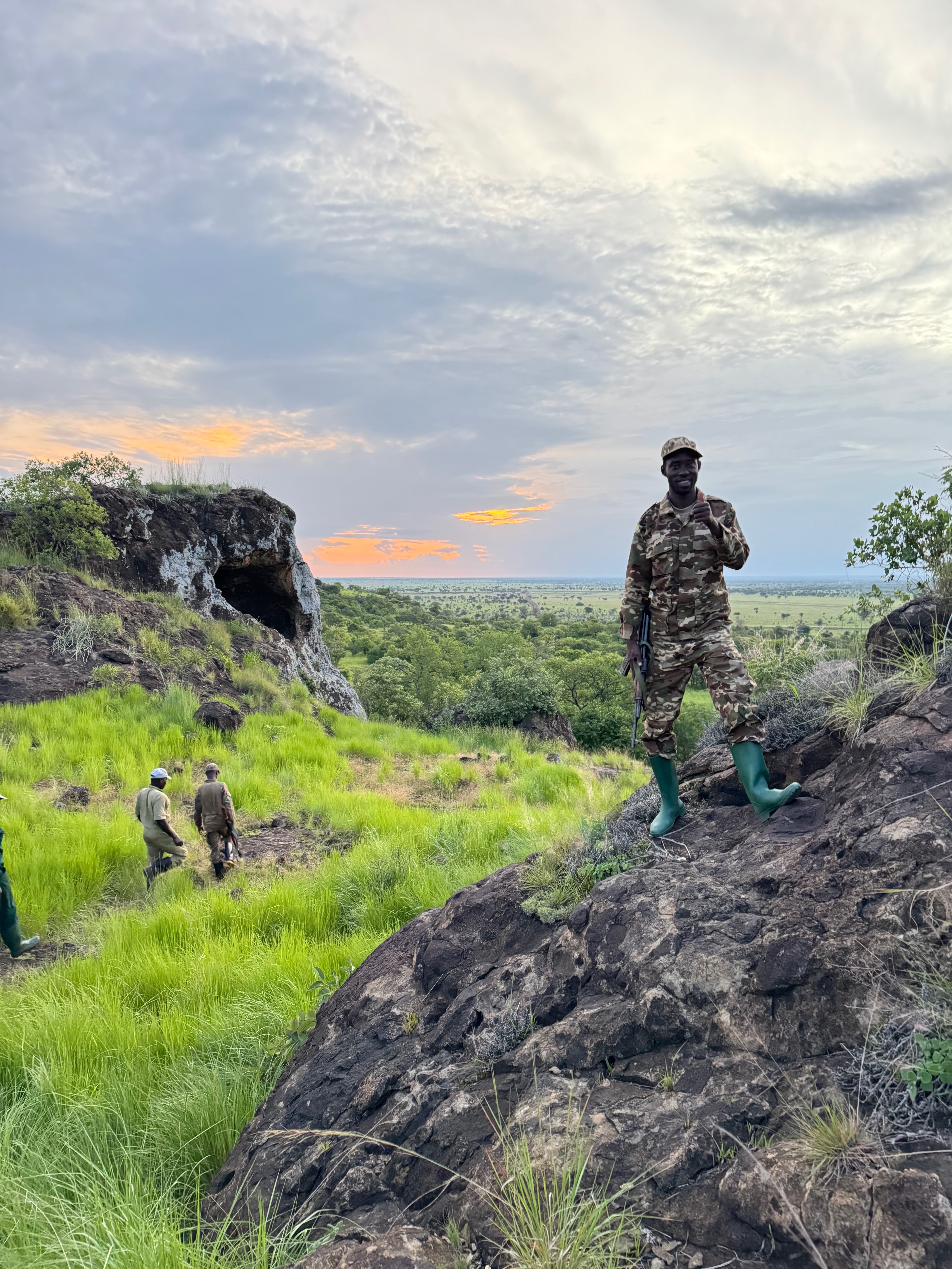 A ranger on a rocky outcrop above the plains at dusk