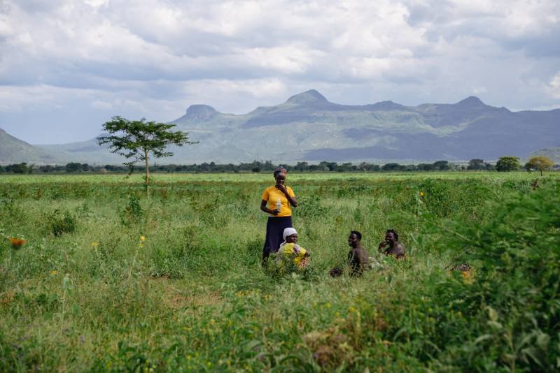 Women resting in a green field with the Karamoja hills behind