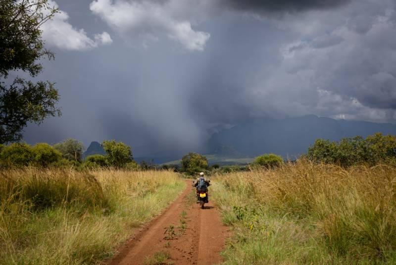A track through the grassland with rain over the mountains