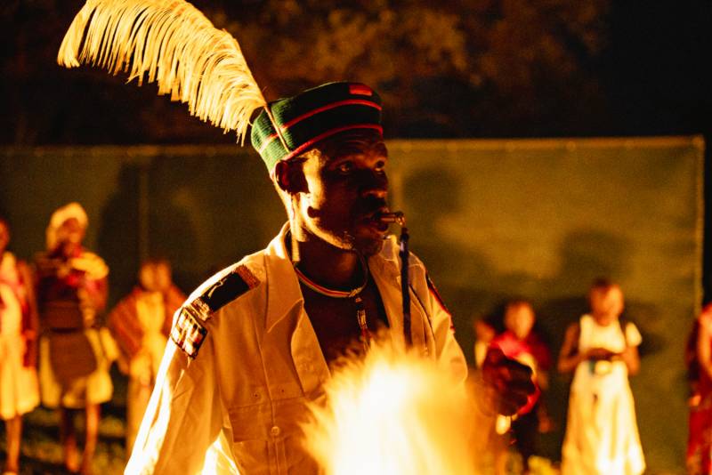 A dancer in a plumed headdress by firelight
