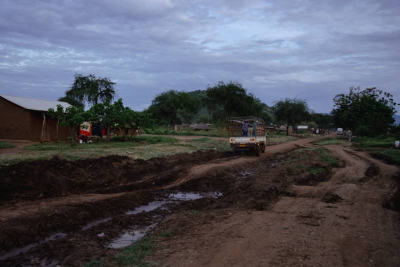 A truck negotiating a washed-out road through a village