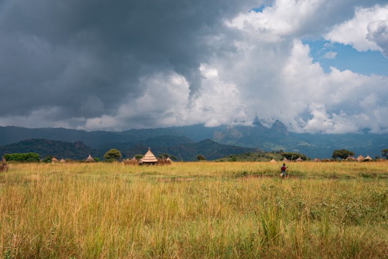 A village of thatched homesteads on the grassland below the mountains
